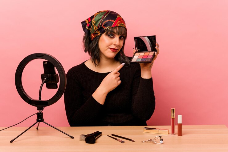Foto mujer joven maquilladora haciendo un tutorial de maquillaje aislado sobre fondo rosa