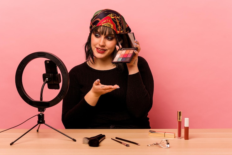 Foto mujer joven maquilladora haciendo un tutorial de maquillaje aislado sobre fondo rosa