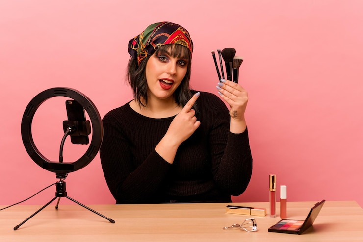 Foto mujer joven maquilladora haciendo un tutorial de maquillaje aislado sobre fondo rosa
