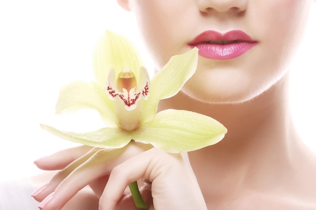 Mujer joven con maquillaje brillante con orquídea