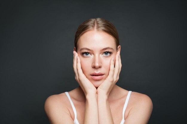 Mujer joven con maquillaje natural en fondo gris