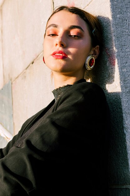 Mujer joven con maquillaje usando pendientes rojos mirando a cámara