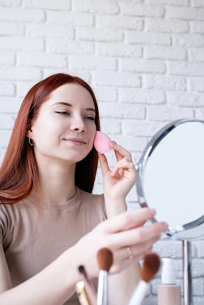 Mujer joven maquillando en casa usando sombras de ojos