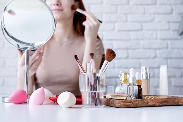 Mujer joven maquillando en casa usando sombras de ojos