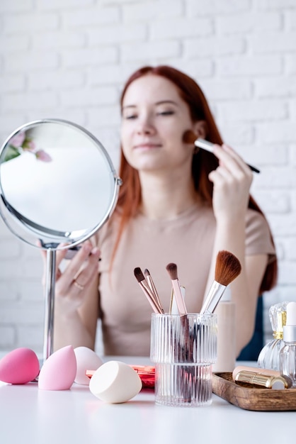 Mujer joven maquillando en casa usando sombras de ojos