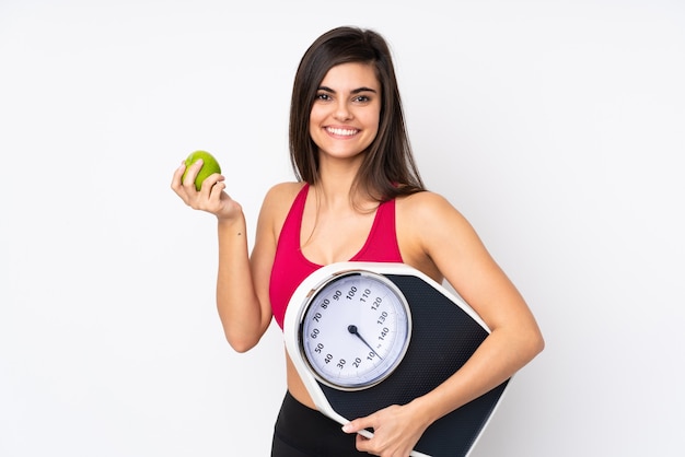 Mujer joven con máquina de pesaje y una manzana