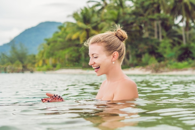 Mujer joven en el mar con estrellas de mar rojas