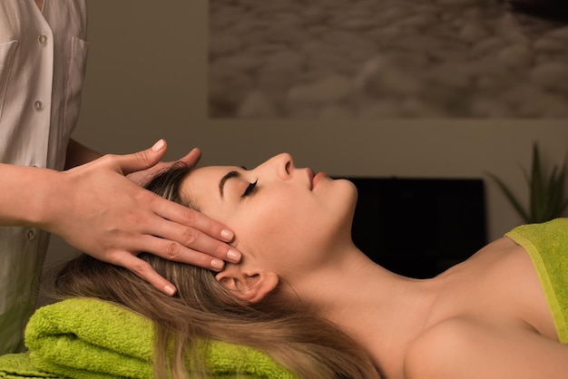 Mujer joven con un masaje facial en el spa