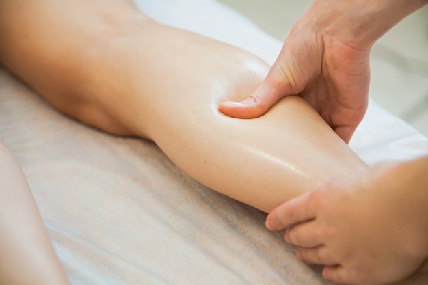 Mujer joven con masaje en el salón de belleza spa Esteticista masajeando las piernas femeninas Concepto de cuidado corporal