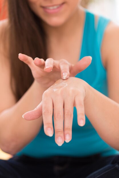 Mujer joven masajeando o aplicando crema en sus manos