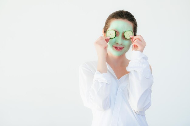 Mujer joven con máscara de arcilla en la cara contra un fondo claro, espacio para texto. Protección de la piel