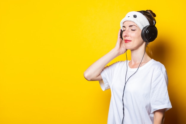 Foto mujer joven con máscara de dormir cerrada y auriculares escuchando música