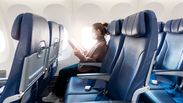 Una mujer joven con máscara facial viaja en avión, nuevo viaje normal después del concepto de pandemia covid-19