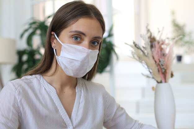 Mujer joven con máscara médica en casa durante la situación epidémica.