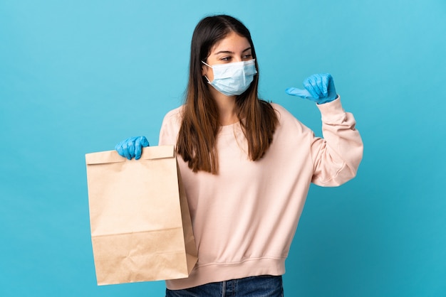 Mujer joven en máscara médica y guantes con una bolsa de papel