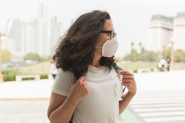 Mujer joven con una máscara médica mientras mira hacia otro lado