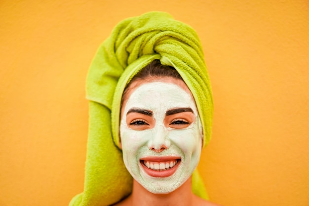 Mujer joven con máscara natural de belleza de pie sobre fondo amarillo - Cuidado de la piel, estilo de vida saludable y concepto de tienda de cosméticos - Centrarse en la nariz