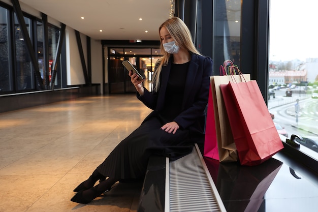 Una mujer joven con una máscara protectora después de ir de compras en un centro comercial