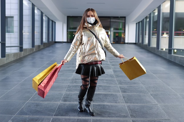 Mujer joven en máscara protectora después de ir de compras