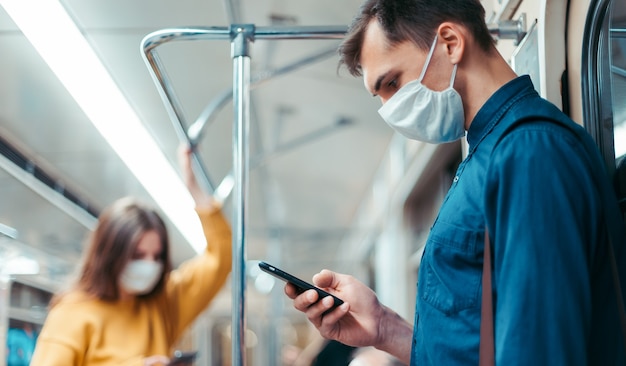 Mujer joven con una máscara protectora de pie en un vagón de metro. coronavirus en la ciudad