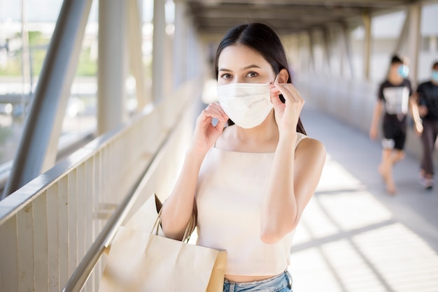 Mujer joven con mascarilla está de pie al aire libre Ciudad