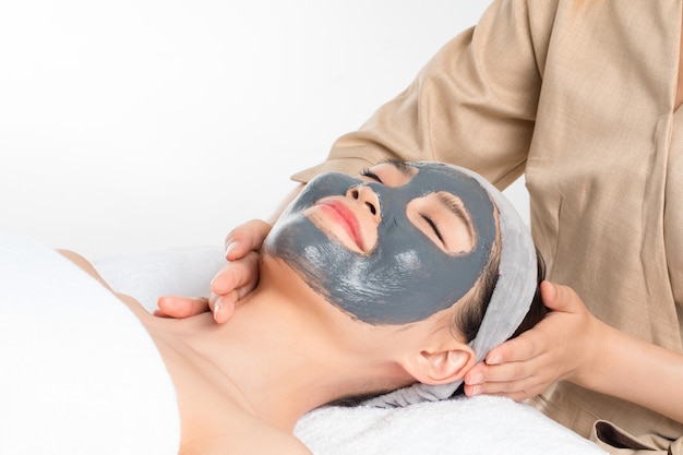 Mujer joven con mascarilla facial en salón de belleza