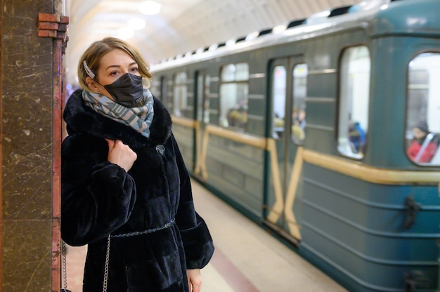 Mujer joven con una mascarilla en el metro