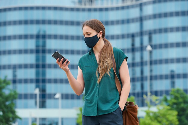 Mujer joven con una mascarilla negra en la ciudad