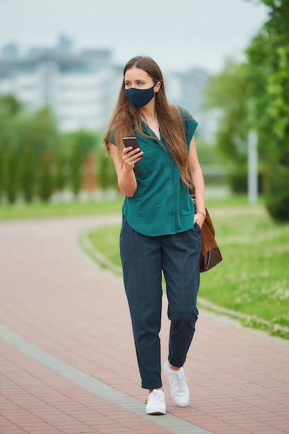 Mujer joven con una mascarilla negra en el parque