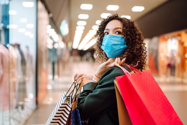 Foto mujer joven con mascarilla de protección contra el coronavirus después de comprar.