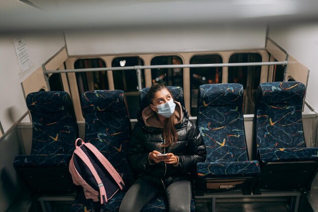 Mujer joven con mascarilla viajando en transporte público