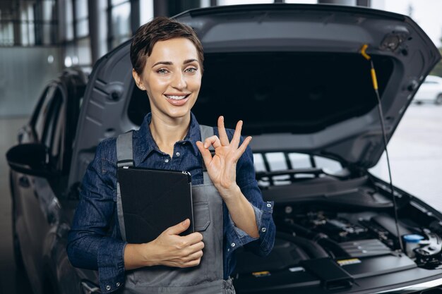 Mujer joven mecánico de automóviles revisando el auto en el servicio de autos