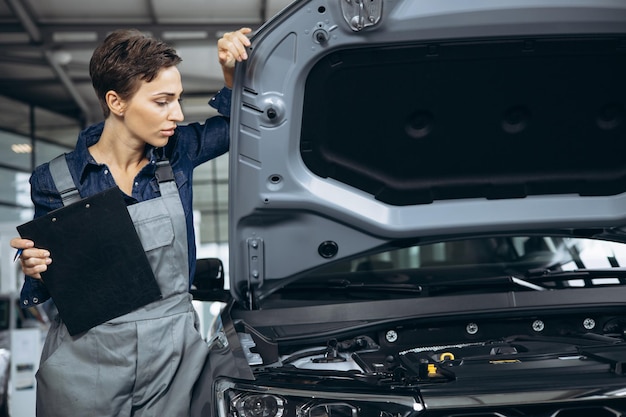 Mujer joven mecánico de automóviles revisando el auto en el servicio de autos