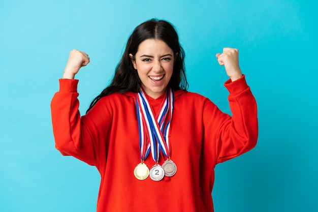 Foto mujer joven con medallas aislado en blanco celebrando una victoria