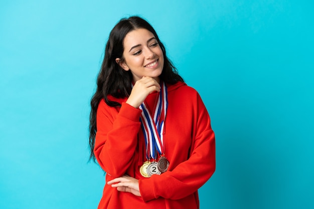 Mujer joven con medallas aislado en la pared blanca mirando de lado