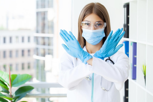 Mujer joven médico europeo cruzando los brazos haciendo signo negativo