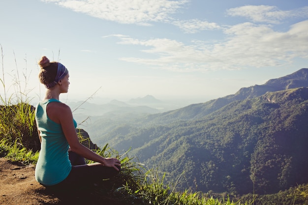 Mujer joven meditando en la cima de una montaña