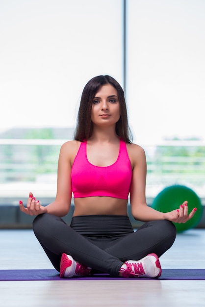 Mujer joven meditando en concepto de salud gimnasio