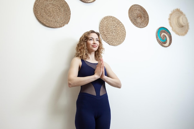 Mujer joven meditando en pose de namaste cerca de la pared