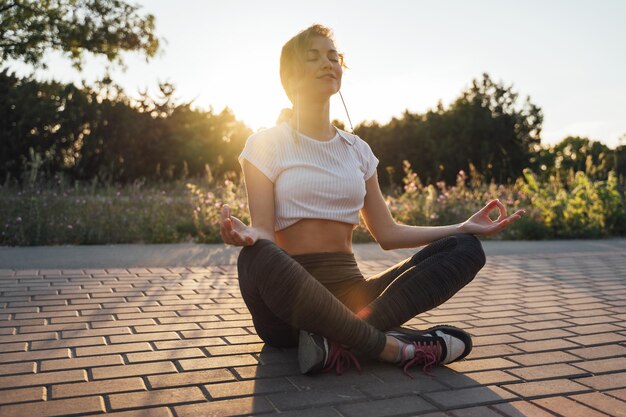 Foto mujer joven meditando en el sendero durante la puesta de sol