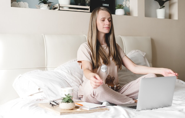 Mujer joven meditar en casa con portátil