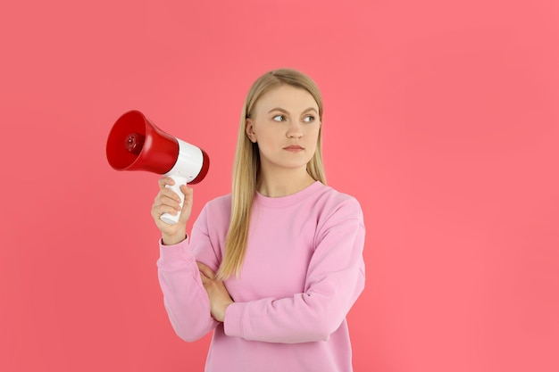 Mujer joven con megáfono sobre fondo rosa