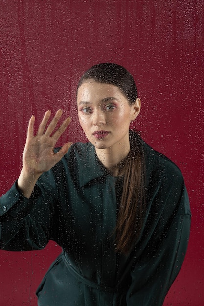 Mujer joven melancólica y triste en la ventana bajo la lluvia