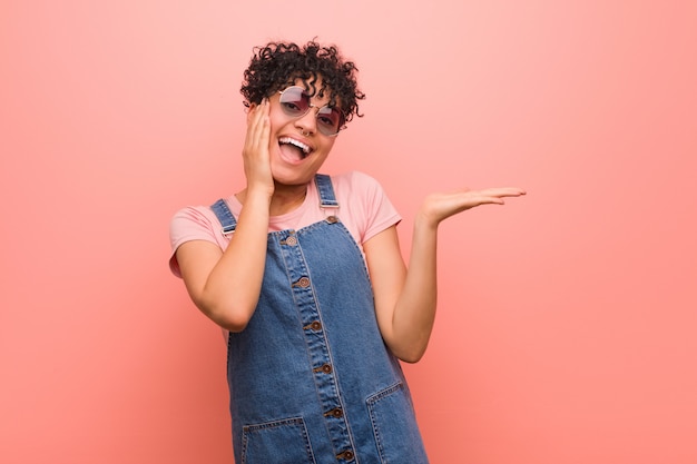 La mujer joven mezclada del adolescente del afroamericano tiene el espacio en blanco en una palma, guarda la mejilla.