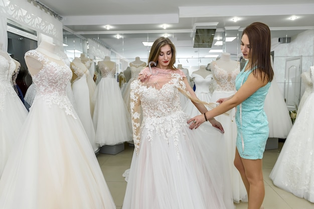 Mujer joven midiendo el vestido de boda para el cliente en el salón