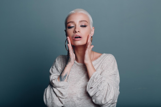 Mujer joven milenaria con retrato de cabello rubio corto haciendo masaje facial de yoga para la piel