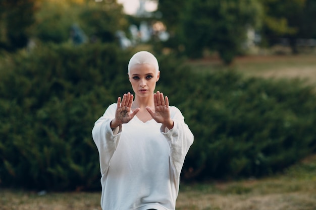 Mujer joven milenaria rubia de pelo corto al aire libre haciendo Qigong