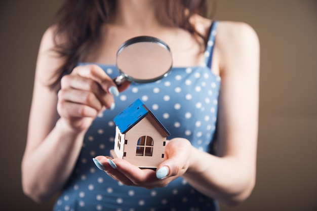 Foto mujer joven mira la casa con una lupa. concepto de búsqueda de inicio