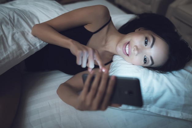 Mujer joven mira el teléfono inteligente.