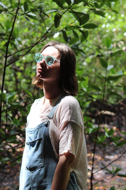 Mujer joven mirando a la cámara en el bosque